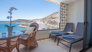 A balcony with wicker chairs, a glass table, and a view of the sea and buildings. - Wake up to Gorgeous Ocean Views from this Chic Apartment (Patalavaca)