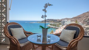 A balcony with wicker chairs, a glass table, and a potted orchid. - Wake up to Gorgeous Ocean Views from this Chic Apartment (Patalavaca)