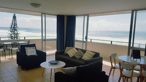A modern living room with a sofa, chairs, a small table, and a view of the ocean. - The Sands (Surfers Paradise)