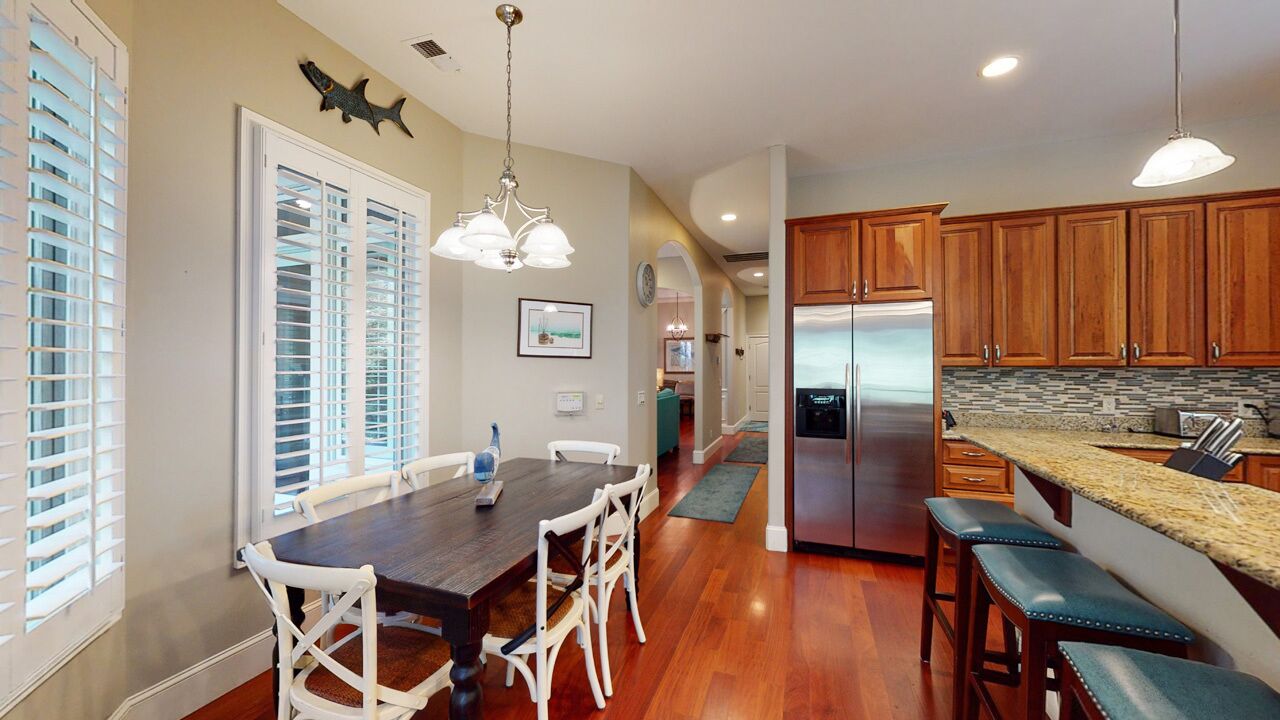 A spacious kitchen with wooden cabinets, a stainless steel refrigerator, and a granite countertop.