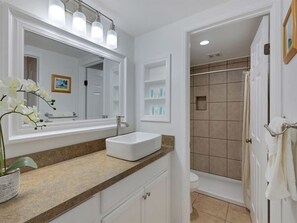 A bathroom with a white sink, a large mirror, and a shower area. - Modern Hawaii Style w/Kitchen, WiFi, Lanai–#205 (KAUNAKAKAI)