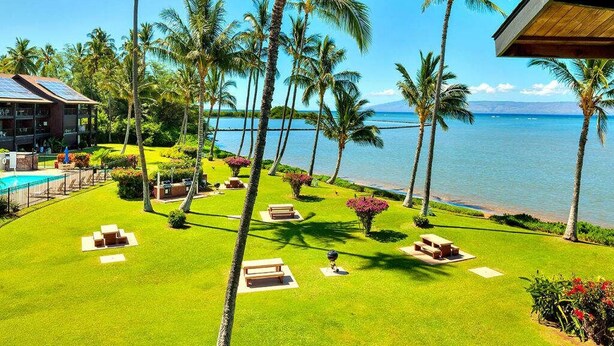 A resort with a pool, palm trees, and a view of the ocean. - Tropical Style w/OF Lanai, Flat Screen, WiFi–#229 (KAUNAKAKAI)