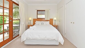 Ein Schlafzimmer mit einem Bett, zwei Nachttischlampen, einem Deckenventilator, einem Fenster mit Vorhängen und einer Tür.