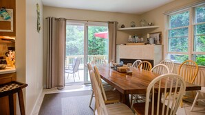 Un comedor con una mesa y sillas de madera, una cocina con estufa, y vistas a zonas verdes exteriores.
