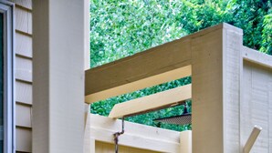 Una verja de madera color beige con un pestillo de metal y una tubería que la atraviesa.