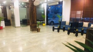 Um hall amplo com piso de mármore, balcão de recepção e área de estar com sofás e mesas.