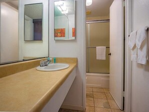 Een badkamer met een wastafel, spiegel en douche.