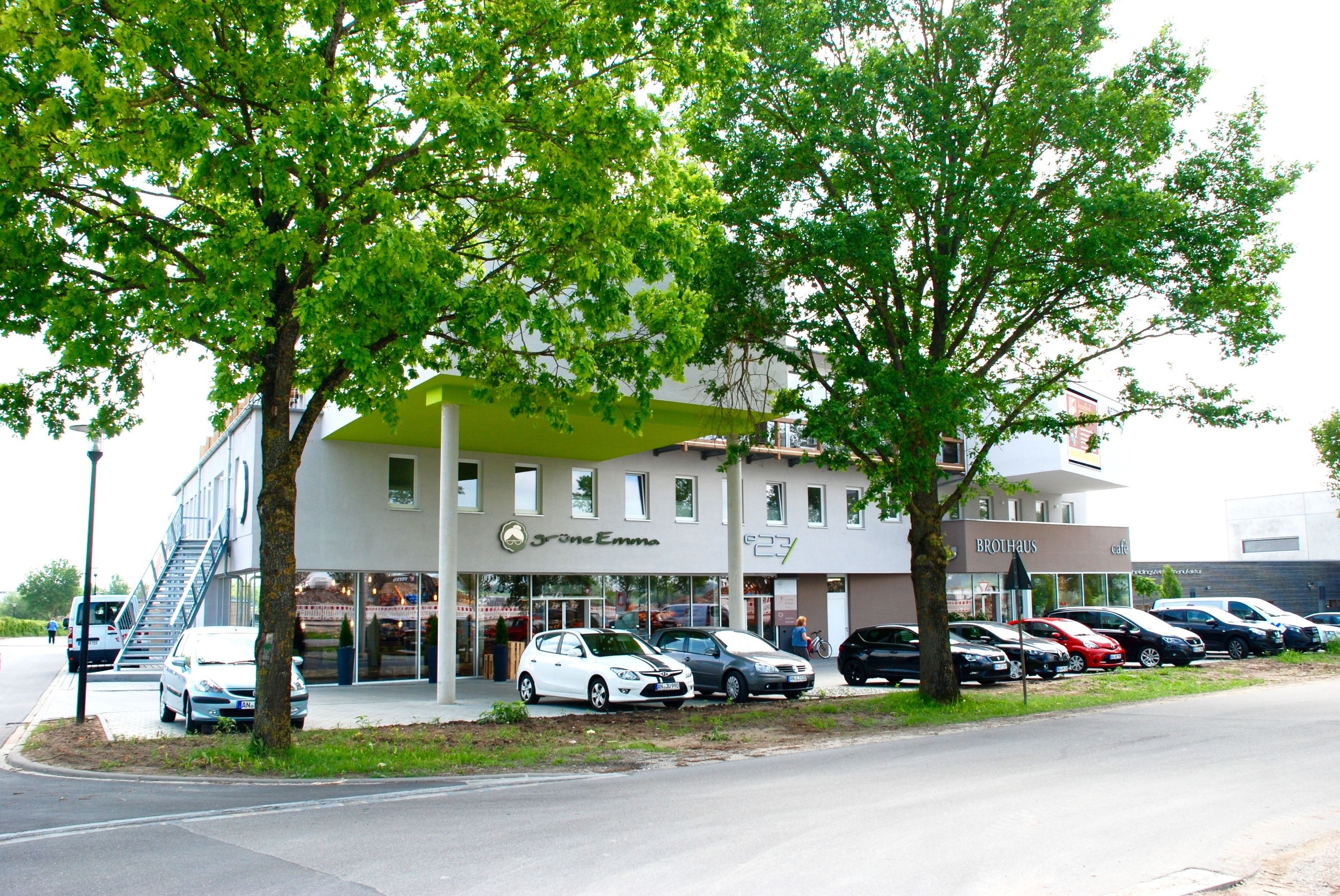 A building with a green awning, a staircase, and a row of parked cars.