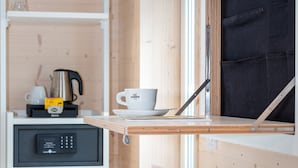 A compact room with a wooden interior, a small kitchenette with a coffee maker, a cup, and a kettle on the counter, and a window with a black blind. - Schlafzimmer Hotel (Dinkelsbuehl)