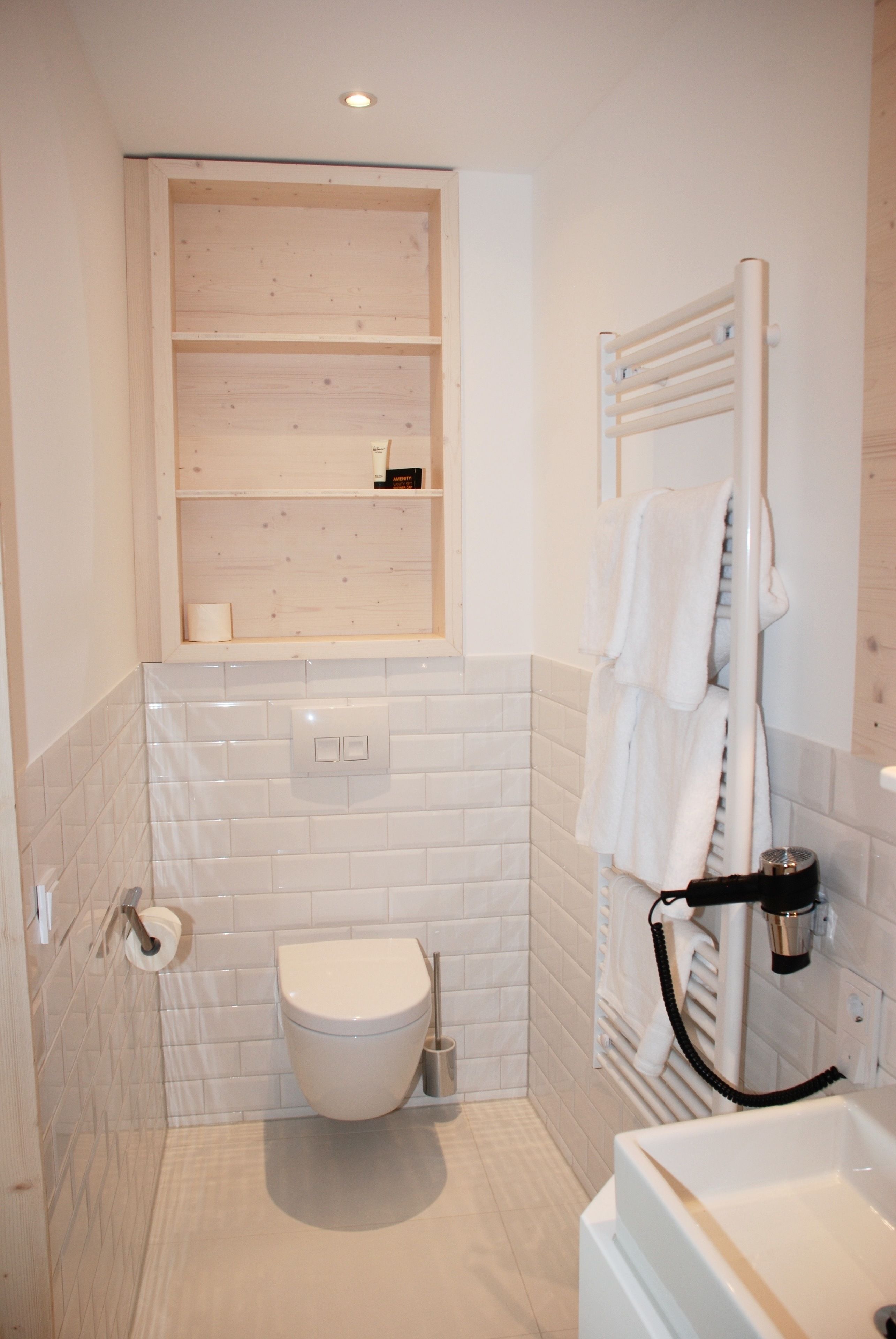 A bathroom with a toilet, a sink, a towel rack, and a window above the toilet.