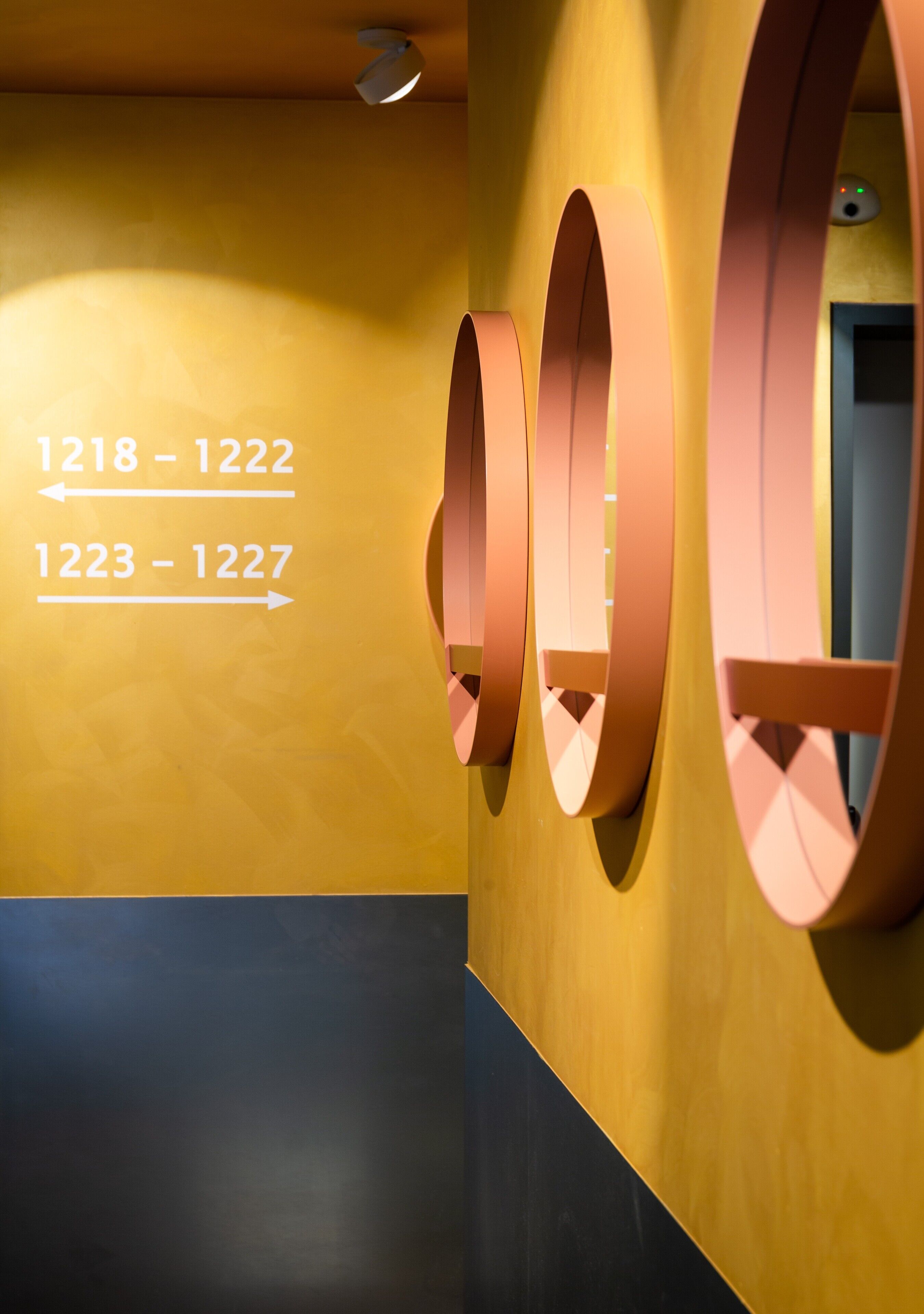 A hallway with directional arrows and numbers indicating room numbers 1218-1222 and 1223-1227.