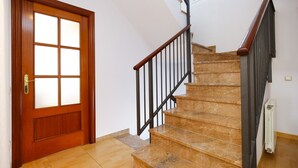 Una puerta de madera con paneles de vidrio esmerilado, una escalera de mármol con barandillas negras y un radiador en la pared.