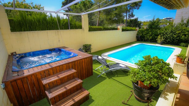 Un patio trasero con un jacuzzi, una piscina y una pequeña escalera que lleva al jacuzzi.