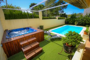 A backyard with a hot tub, a swimming pool, and a small staircase leading to the hot tub. - House with private pool - Families only (Salou)