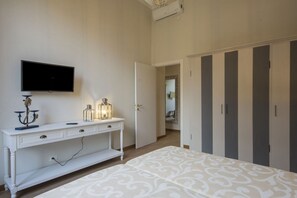 A bedroom with a bed, a TV, a bedside table with a lamp, and a wardrobe.
