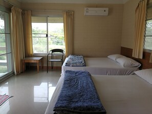 Habitación de hotel con dos camas, una silla, una mesa y una ventana con cortinas.