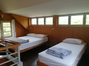 Una habitación con dos camas, paredes de madera y ventanas amplias.