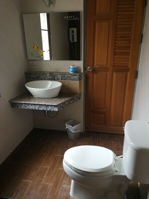 Un baño con un lavabo blanco, un espejo, una puerta de madera y un inodoro.