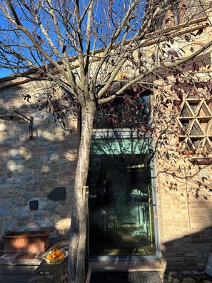 A stone building with a tree in front, a window, and a door. - Renovated detached villa with a fireplace and air conditioning. (castelnuovo beradenga, siena)