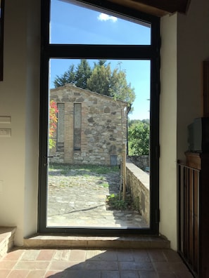A stone building with a window and a door leading to a courtyard.