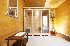 Un intérieur en bois comprenant une table, un banc et une porte-fenêtre coulissante donnant accès à une salle de bain.