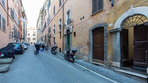 Une rue étroite bordée de bâtiments historiques, de motos et de voitures garées.
