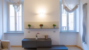 A modern room with two windows, a wall-mounted shelf with potted plants, a built-in bench, and a wall-mounted light fixture. - Purificazione Hi-Tech Apartment (Rome)