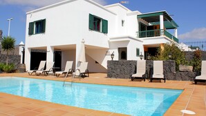 A two-story white building with a swimming pool, outdoor seating, and a stone wall. - Villa Leonard in Playa Blanca (Playa Blanca)