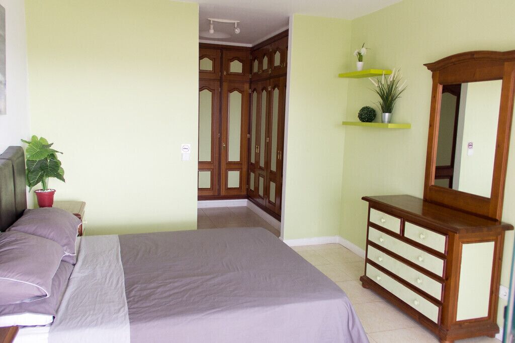 Une chambre à coucher comprenant un lit, une commode, un miroir et un placard aux portes en bois.