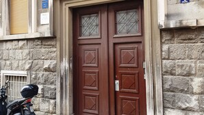 A building with a double wooden door, stone walls, and a motorbike parked in front.