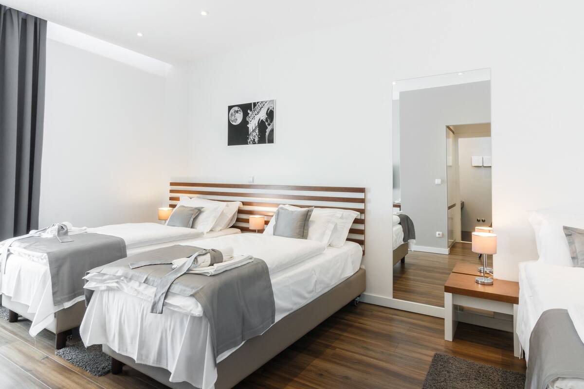 A modern hotel room with a large bed, two bedside tables, a mirror, and a wall-mounted artwork.