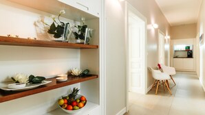 A modern kitchen with white cabinets, wooden shelves, and a fruit bowl.