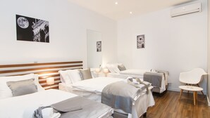 A hotel room with two beds, a sitting area, and artwork on the walls.