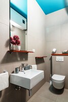 A modern bathroom with a white sink, a toilet, and a mirror above the sink.