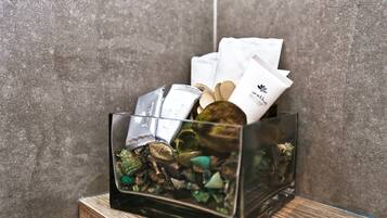 A clear glass container with various items including a small aquarium, a wooden spoon, and some white packets.