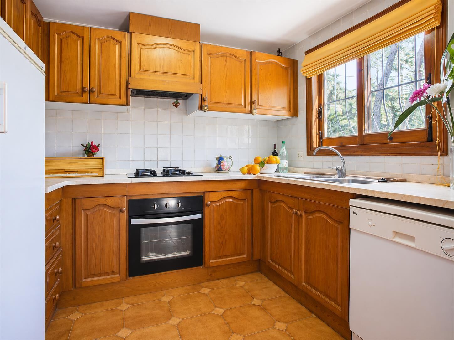 Une cuisine avec des meubles de rangement en bois, une cuisinière, un four, un lave-vaisselle et une fenêtre donnant sur la forêt.