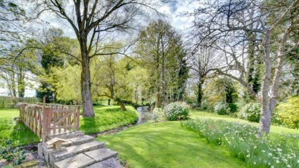 Un jardin avec un sentier de pierres menant à un pont en bois.