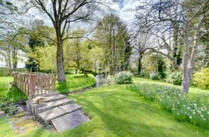 A garden with a stone pathway leading to a wooden bridge.