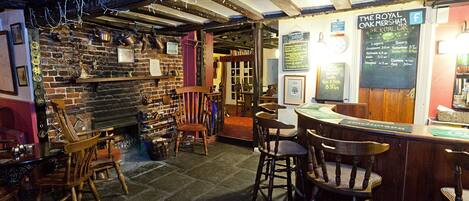 Ein gemütliches Pub-Interieur mit freiliegenden Backsteinwänden, Holzmöbeln und einer Bar.