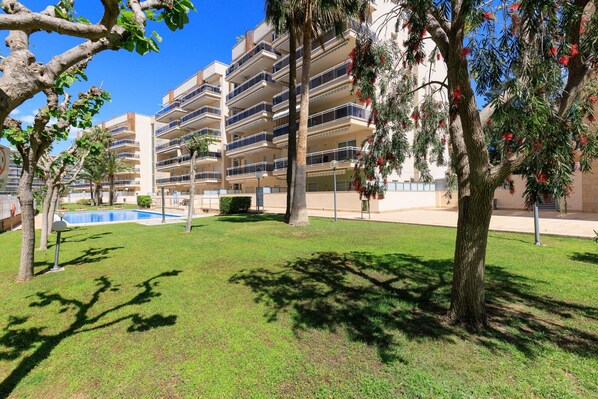 A multi-story residential building with balconies, a swimming pool, and well-maintained lawns.