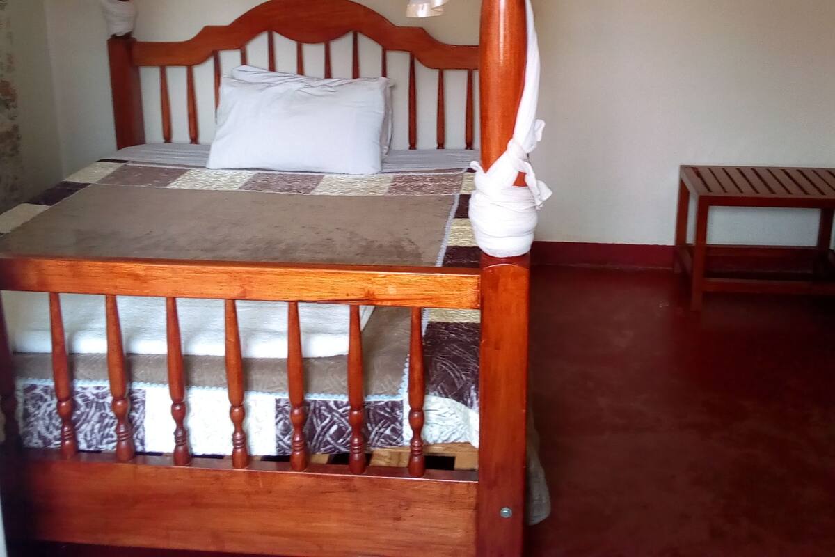 A wooden bed with a canopy, a bedside table, and a wall-mounted shelf.