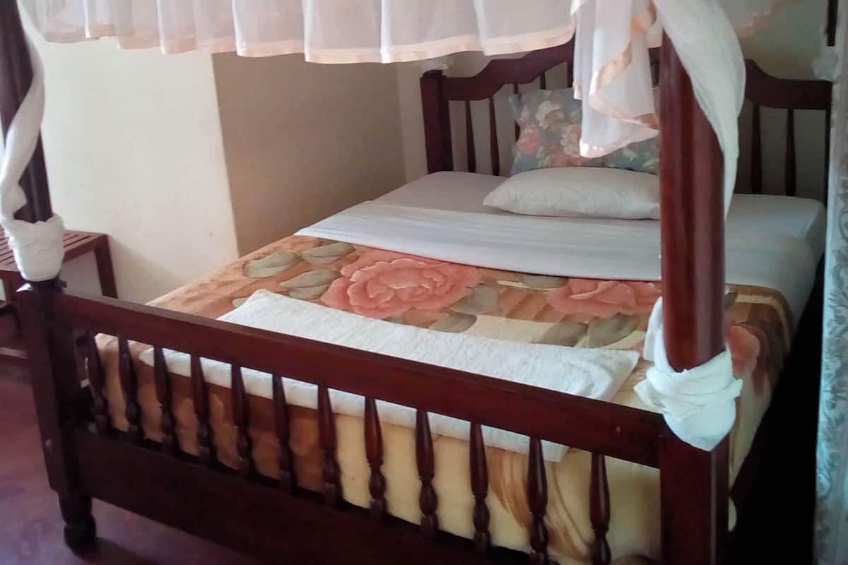 A wooden bed with a canopy and floral bedding.