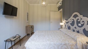 Una camera da letto con un letto, una televisione, una cassettiera, un comodino e un lampadario.