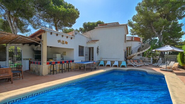 A swimming pool with a tiled edge, a bar area with stools, and a covered seating area with umbrellas. - Escabusso 6 pax - Javea, Costa Blanca (Javea)