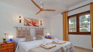A hotel room with a bed, bedside tables, a ceiling fan, artwork, and a window with curtains. - Escabusso 6 pax - Javea, Costa Blanca (Javea)