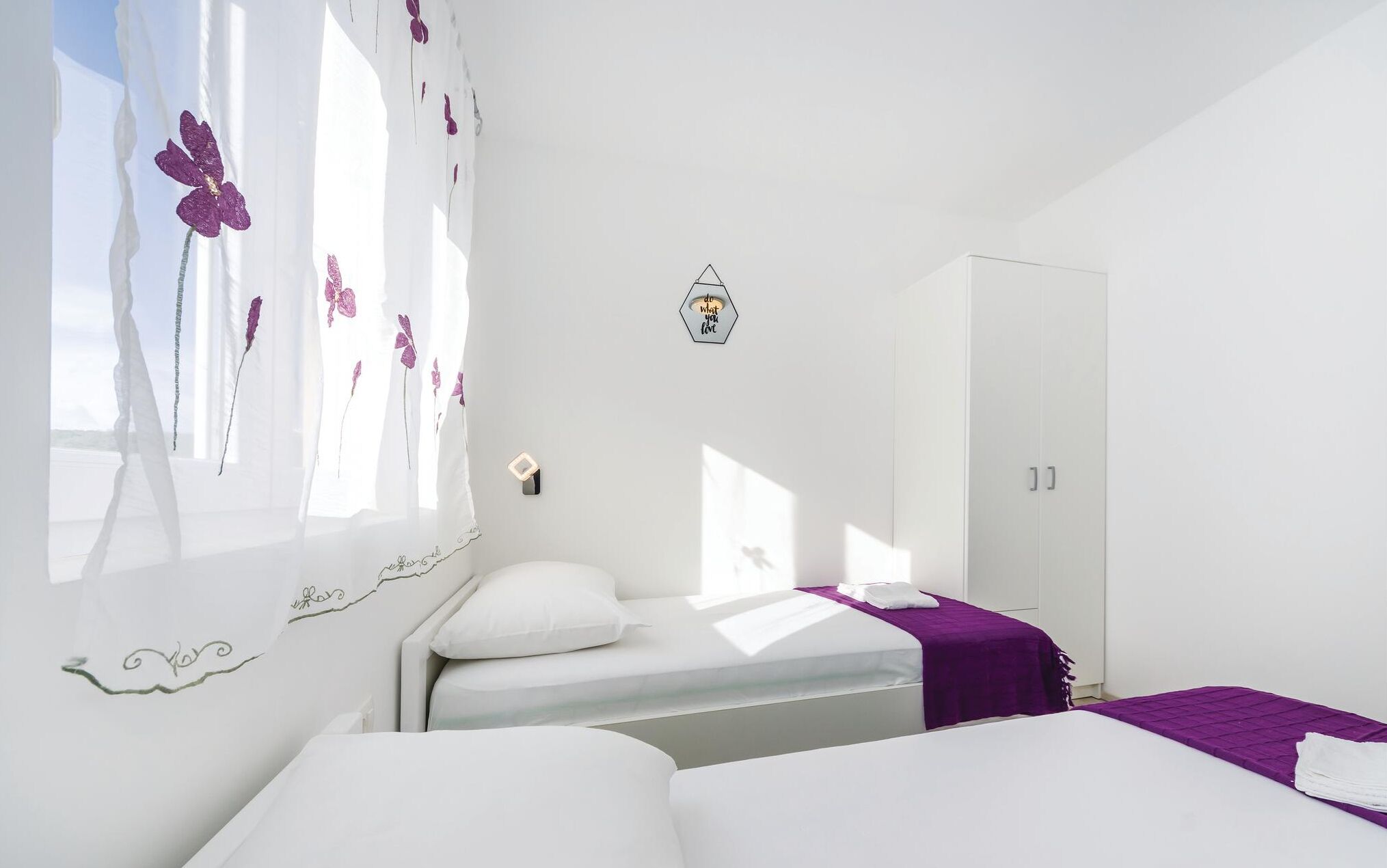 A bedroom with a bed, a wardrobe, and a window with floral curtains.