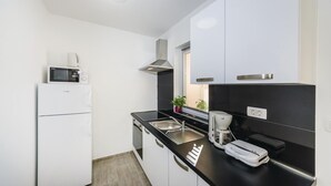 Eine kleine Küche mit weißen Schränken, einer schwarzen Arbeitsplatte, einer Mikrowelle, einer Kaffeemaschine und einem Toaster.