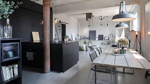Una cocina moderna con una isla central, muebles negros y lámparas colgantes.