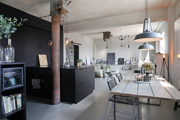 A modern kitchen with a central island, black cabinetry, and pendant lighting.