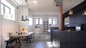 Una cocina moderna con una isla central, luces colgantes y vistas al comedor.